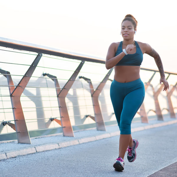 Woman running, motivated to overcome a weight loss plateau.